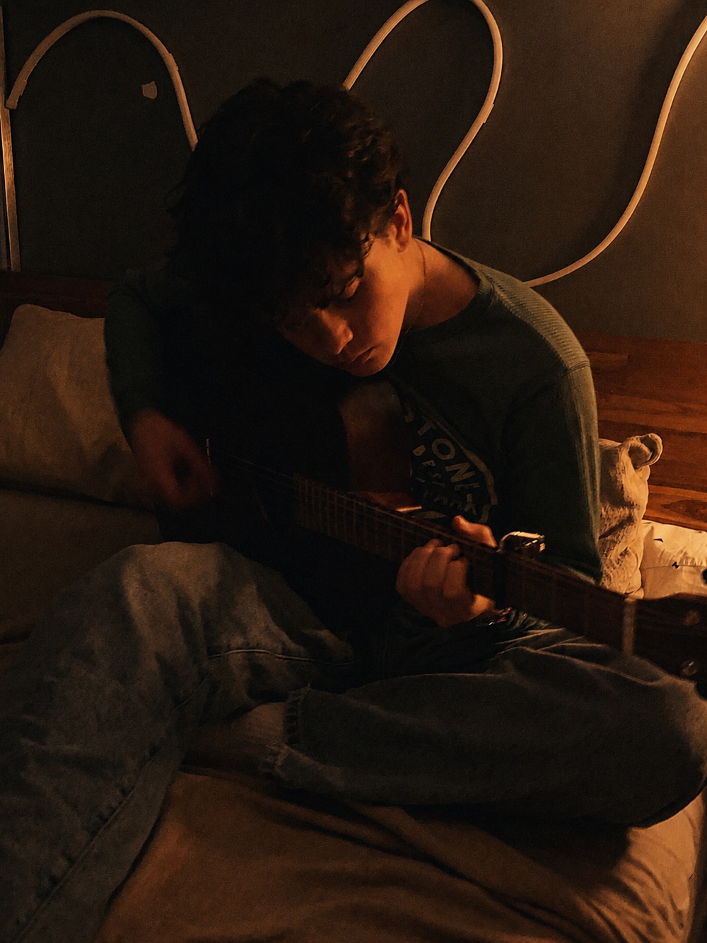 A quiet moment playing guitar, photographed in soft indoor light.