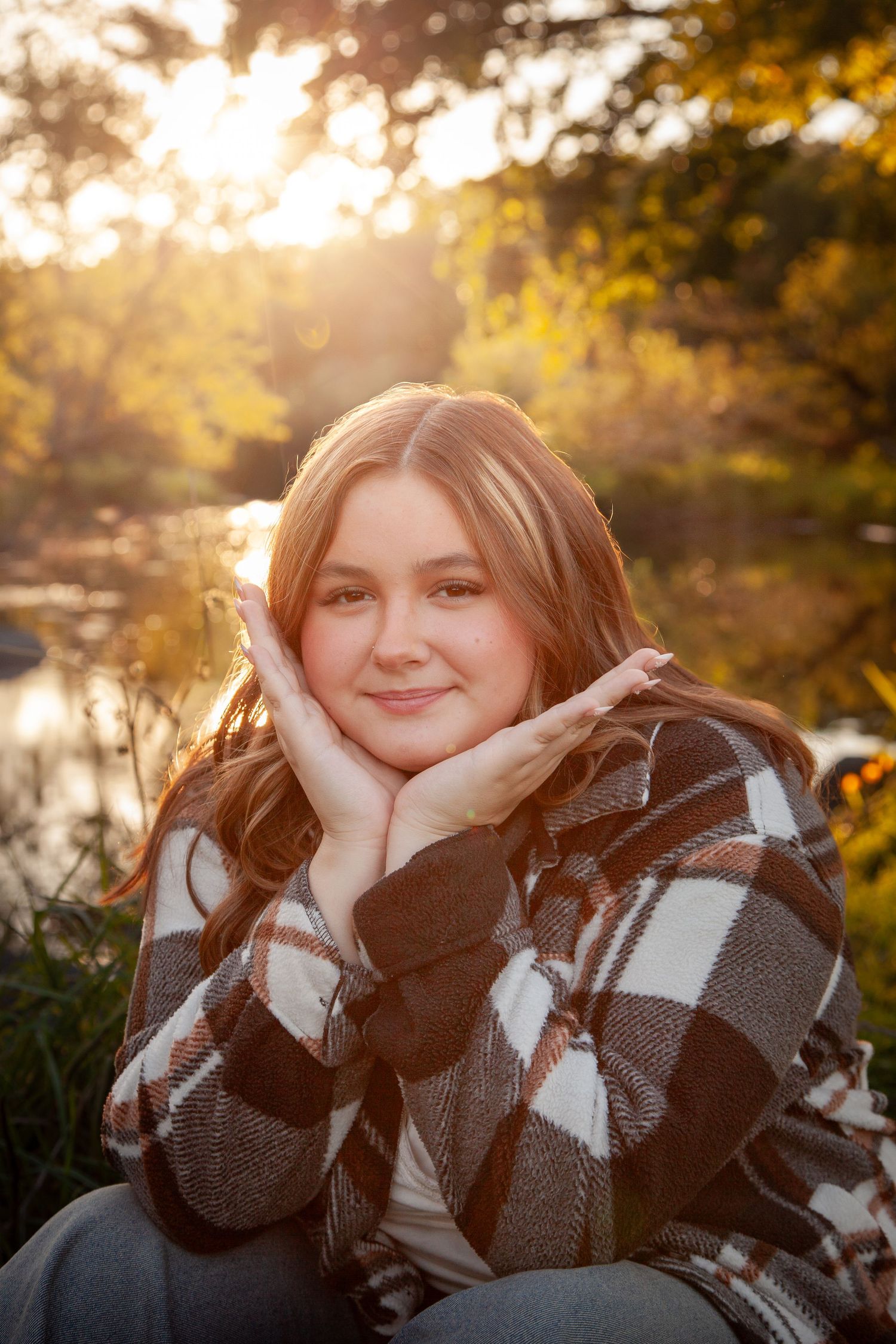 A smiling outdoor portrait with hands framing the face.